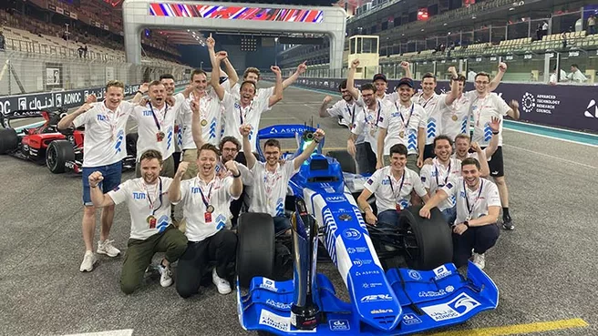 Dem Team der TUM gelang ein spektakuläres Rennen mit einem KI-gesteuerten Rennwagen Das Entwicklerteam mit dem KI gesteuerten Rennwagen nach dem Sieg in Abu Dhabi