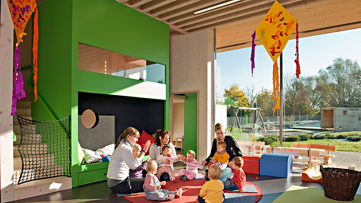 Kinder und Erzieherinnen beim Spiel auf dem Fußboden in einem hellen freundlichen Gemeinschaftsraum des Ingeborg-Ortner-Kinderhauses.  Foto: Astrid Eckert / TUM